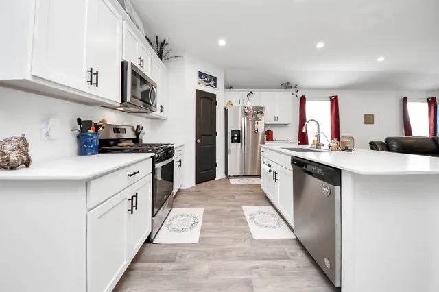 a kitchen with stainless steel appliances a sink dishwasher stove refrigerator and cabinets