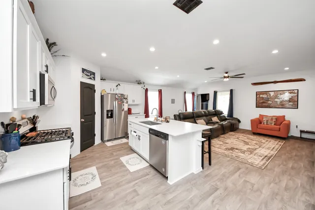 a kitchen with stainless steel appliances kitchen island granite countertop a refrigerator and a sink