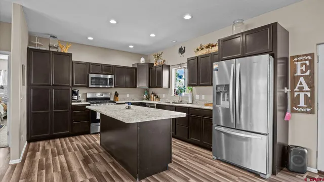 a kitchen with kitchen island granite countertop stainless steel appliances and refrigerator