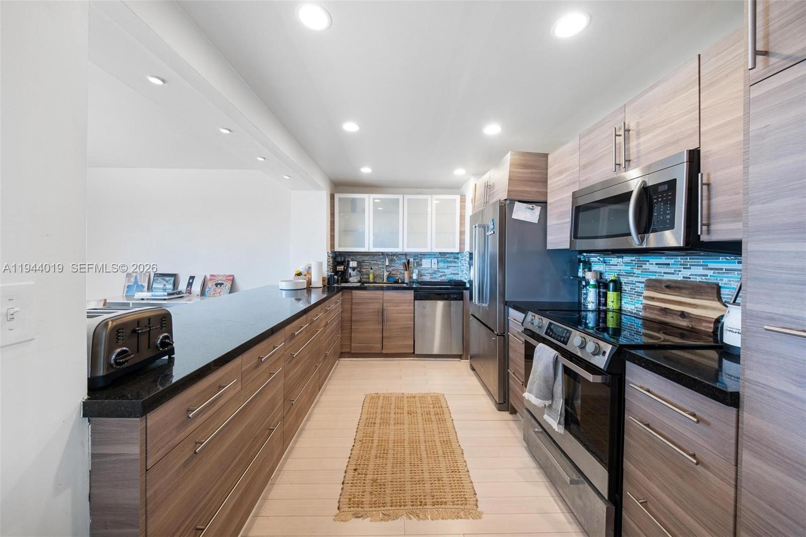 11111 Biscayne Boulevard, Unit 2D Miami, FL 33181 - Photo 9 of 26 a kitchen with stainless steel appliances granite countertop a sink a stove top oven a counter space and cabinets