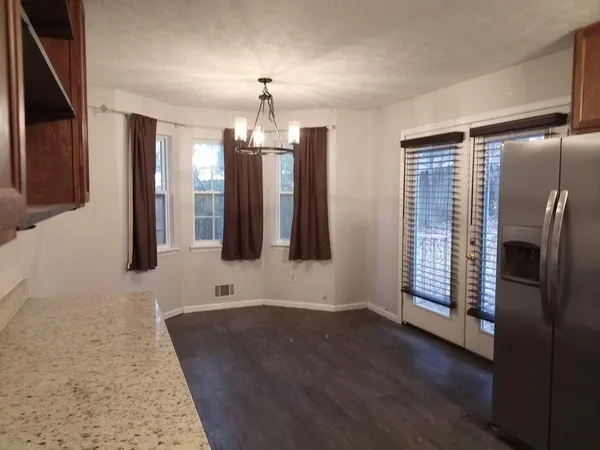 an empty room with wooden floor and chandelier