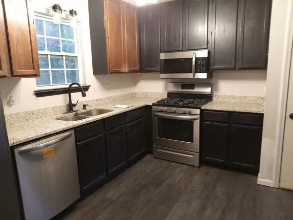 a kitchen with granite countertop stainless steel appliances a stove a sink and a microwave