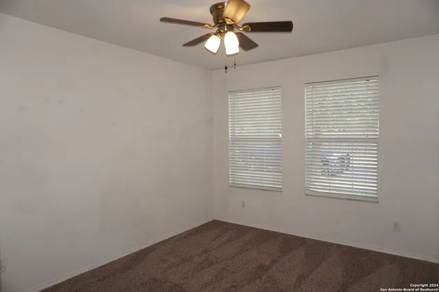 an empty room with a window and a fan