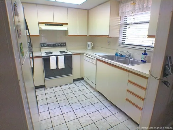 a kitchen with a sink a stove cabinets and a window