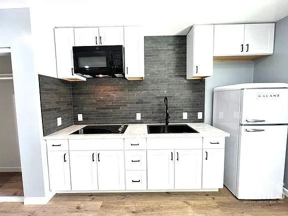 a kitchen with granite countertop a stove top oven a sink a window and a refrigerator