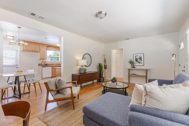 a living room with furniture kitchen view and a large window