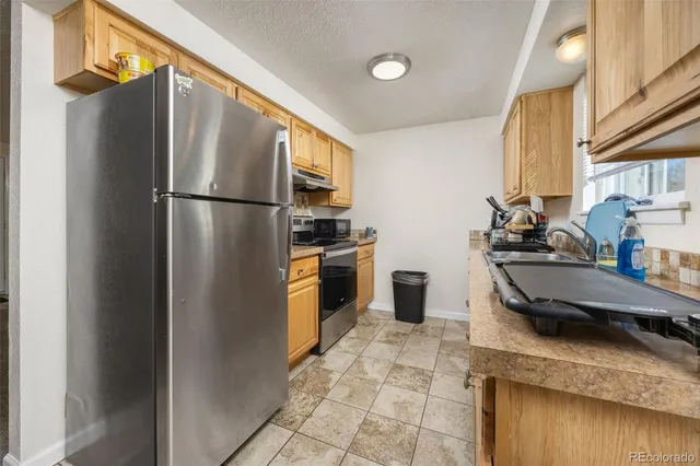 a kitchen with stainless steel appliances granite countertop a refrigerator a sink and a stove