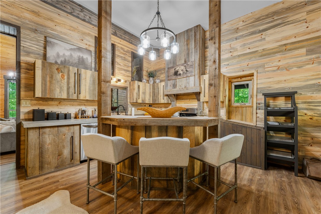 3931 Zack Road Marshall, AR 72650 - Photo 6 of 56 Kitchen with wooden walls, light wood-type flooring, suspended lighting, stainless steel appliances, and a kitchen bar