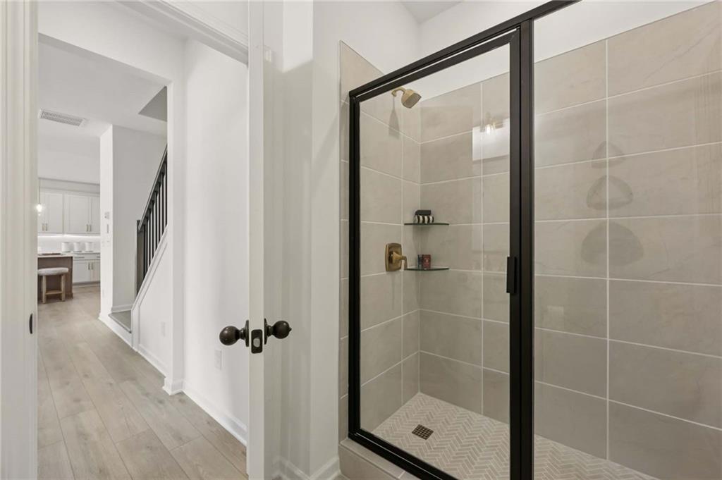 6145 Kismet Road Buford, GA 30518 - Photo 22 of 43 a bathroom with a glass shower door and a glass door