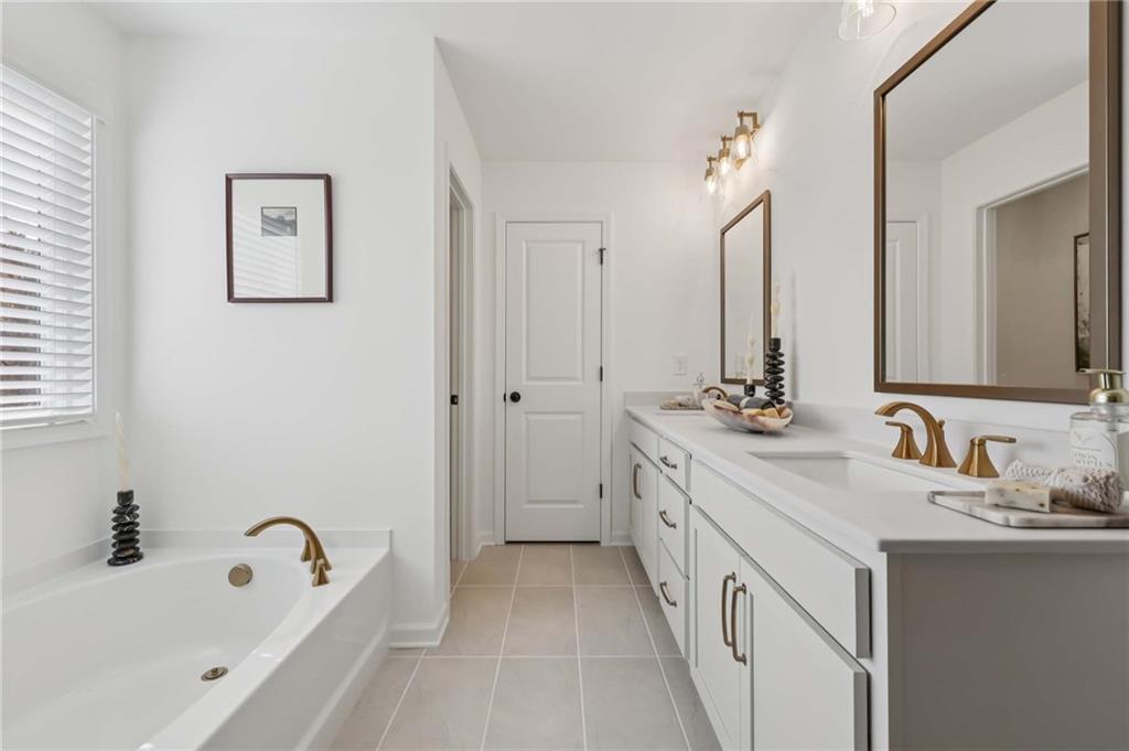 6145 Kismet Road Buford, GA 30518 - Photo 40 of 43 a bathroom with a double vanity sink and a bathtub