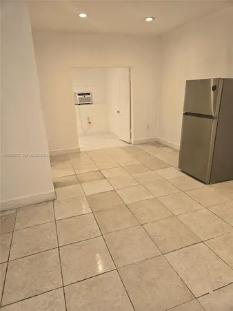 a view of a refrigerator in kitchen and an empty room