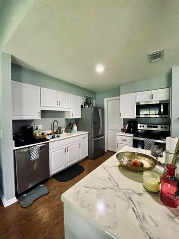 a kitchen with stainless steel appliances kitchen island granite countertop a sink dishwasher stove top oven and refrigerator