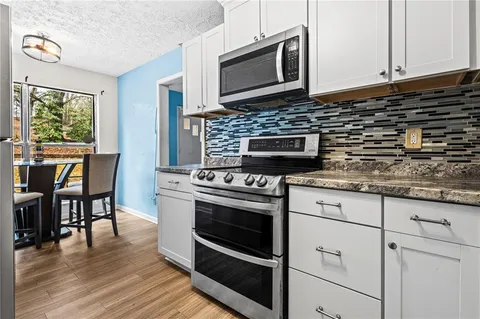 a kitchen with granite countertop cabinets stainless steel appliances and a wooden floor
