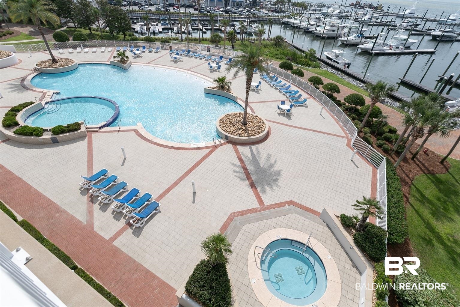 27800 Canal Road, Unit 411 Orange Beach, AL 36561 - Photo 29 of 49 Expansive pool deck featuring a lagoon-style pool, integrated hot tub, and paver surfacing with brick accents