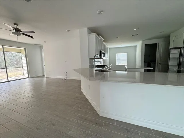 an empty room with wooden floor and kitchen view