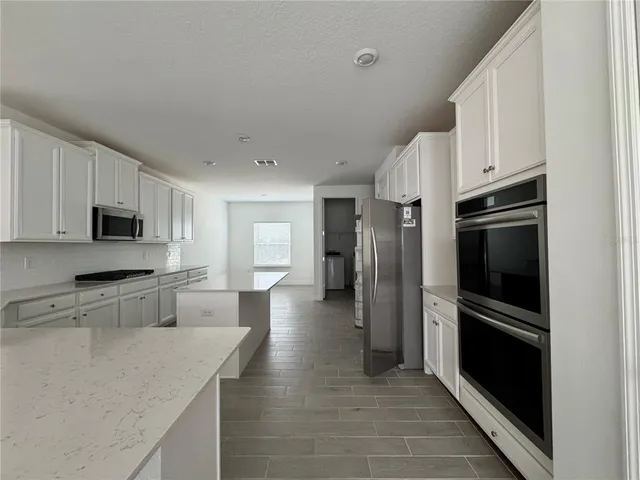 a kitchen with stainless steel appliances granite countertop a refrigerator and a stove top oven
