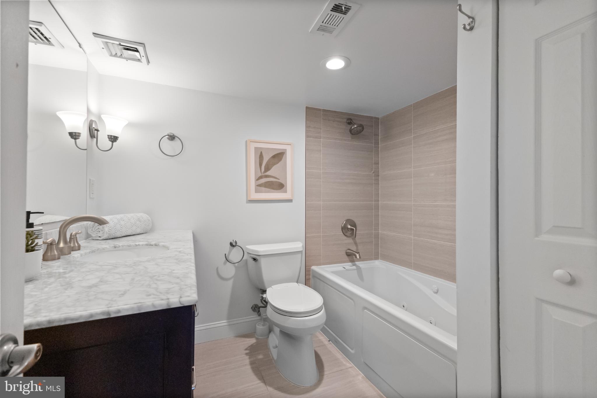 700 7th Street Southwest, Unit 813 Washington, DC 20024 - Photo 22 of 26 a bathroom with a granite countertop sink a toilet and bathtub