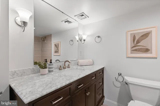 a bathroom with a granite countertop sink a toilet and mirror