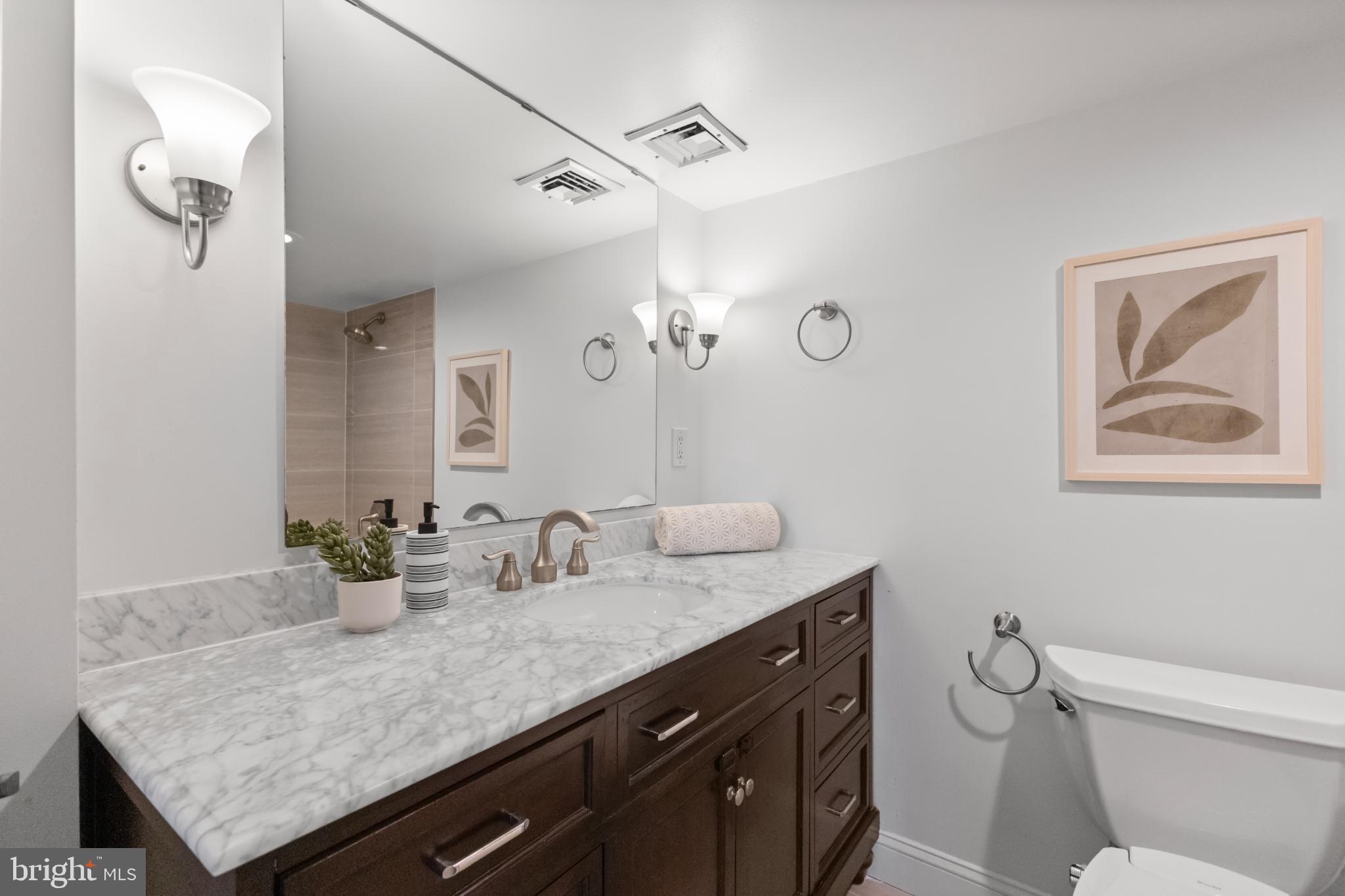 700 7th Street Southwest, Unit 813 Washington, DC 20024 - Photo 23 of 26 a bathroom with a granite countertop sink a toilet and mirror