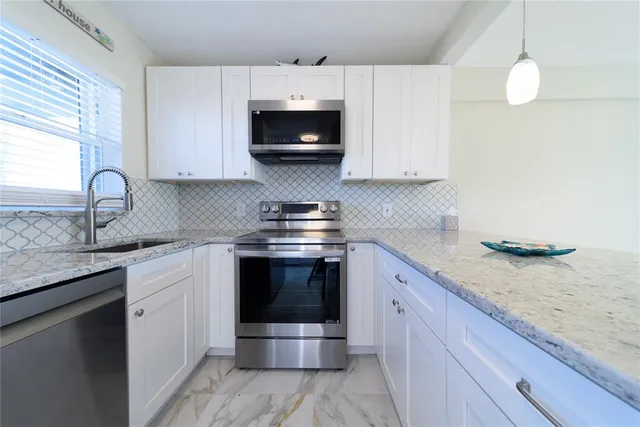 a kitchen with stainless steel appliances granite countertop a sink stove and microwave
