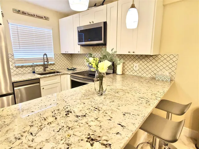 a kitchen with granite countertop sink cabinets and stainless steel appliances