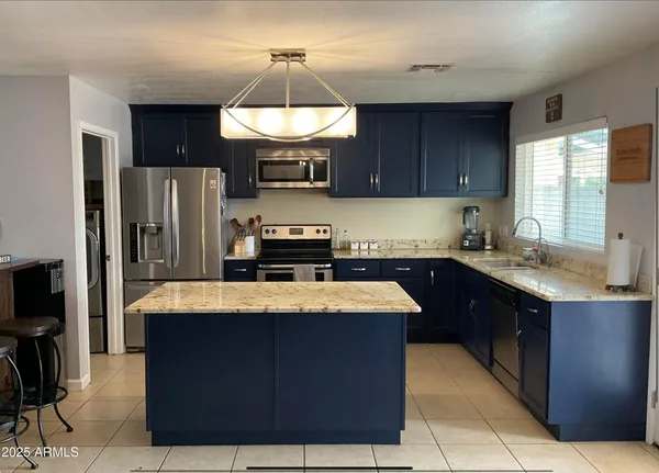 a kitchen with stainless steel appliances granite countertop wooden cabinets a refrigerator and a sink