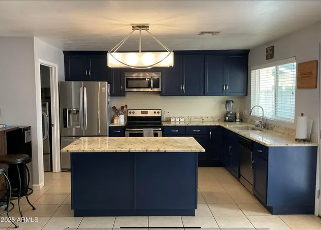 a kitchen with stainless steel appliances granite countertop wooden cabinets a refrigerator and a sink