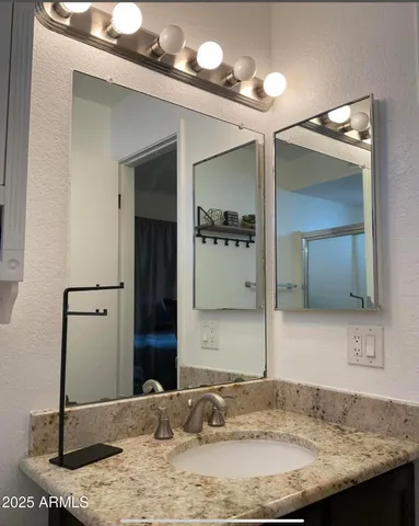 a bathroom with a granite countertop sink and a mirror