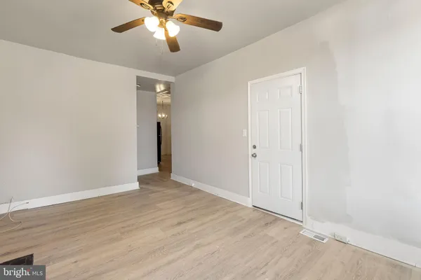 an empty room with wooden floor closet and windows