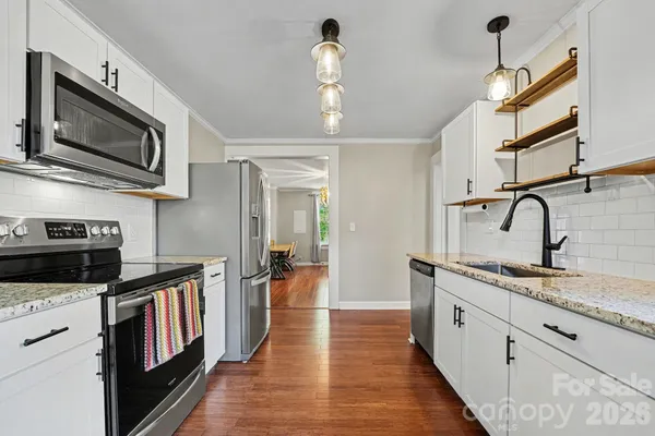 a kitchen with stainless steel appliances granite countertop a sink dishwasher a stove and a microwave oven with wooden floor