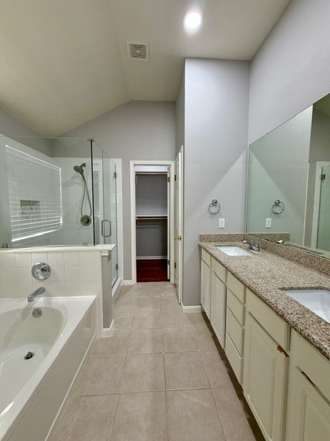 708 Ranier Lane Round Rock, TX 78665 - Photo 14 of 20 Full bathroom featuring a shower stall, double vanity, vaulted ceiling, a spacious closet, and a bath