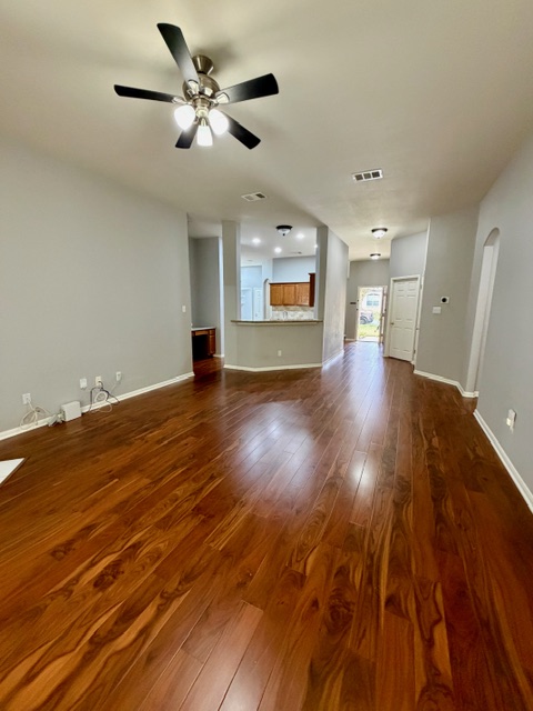 708 Ranier Lane Round Rock, TX 78665 - Photo 5 of 20 Unfurnished living room with dark wood finished floors, ceiling fan, and arched walkways