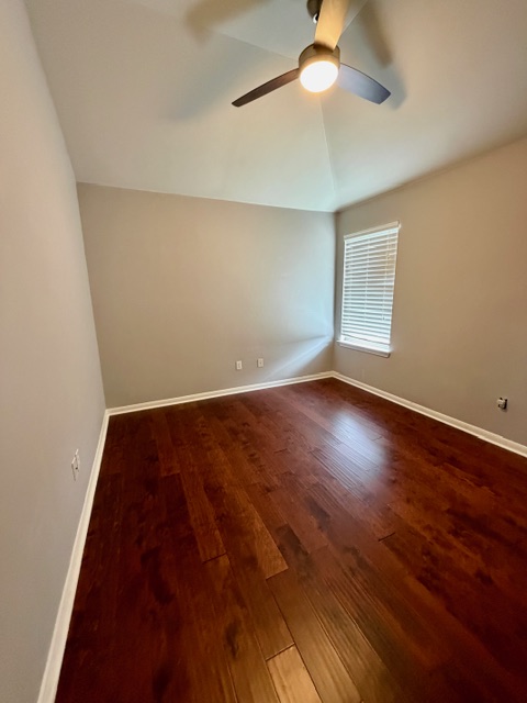 708 Ranier Lane Round Rock, TX 78665 - Photo 9 of 20 Spare room with dark wood-style flooring, ceiling fan, and vaulted ceiling