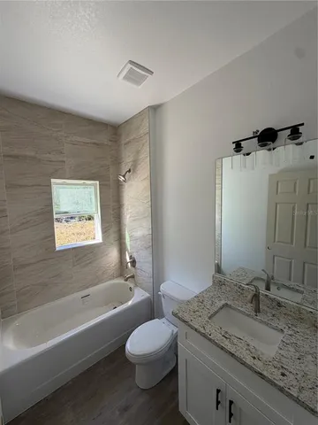 a bathroom with a granite countertop sink toilet and bathtub