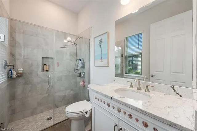 a bathroom with a granite countertop sink a toilet and shower