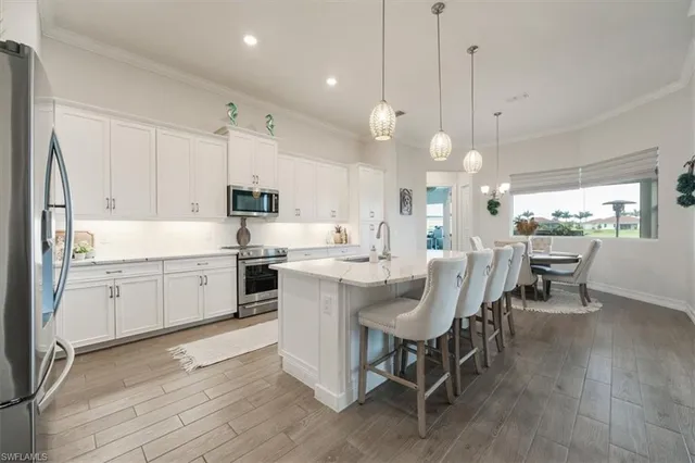 a large white kitchen with lots of furniture a sink appliances and dining table
