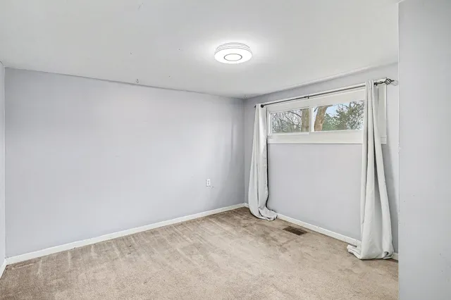 a view of an empty room with closet and a window