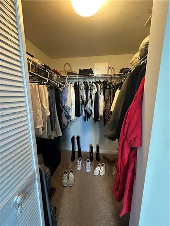 a view of walk in closet with clothes and shoes