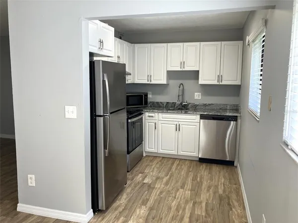 a kitchen with stainless steel appliances granite countertop white cabinets and a stove a oven with white countertops
