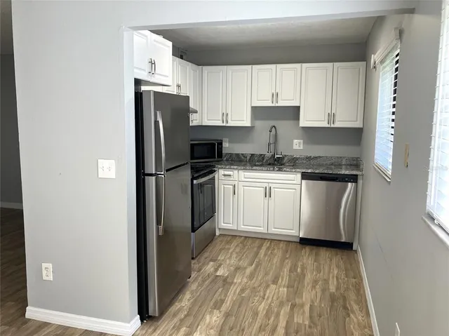a kitchen with stainless steel appliances granite countertop white cabinets and a stove a oven with white countertops