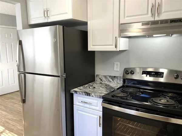 a kitchen with stainless steel appliances a refrigerator a stove and white cabinets