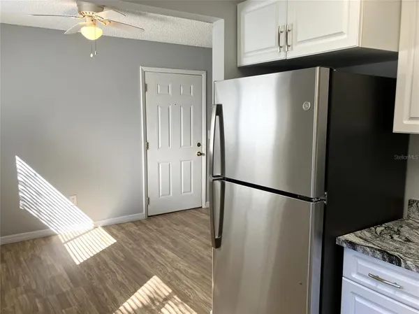 a kitchen with granite countertop a refrigerator sink and white cabinets