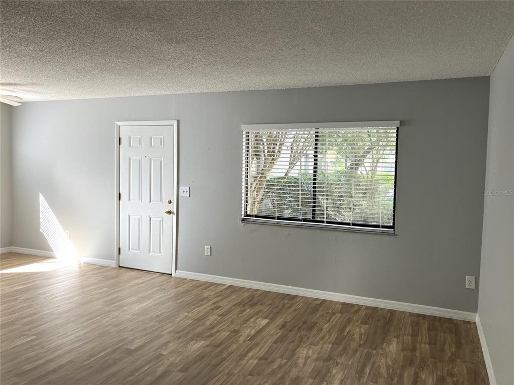 11703 Raintree Village Boulevard, Unit B Temple Terrace, FL 33617 - Photo 7 of 60 an empty room with wooden floor and windows