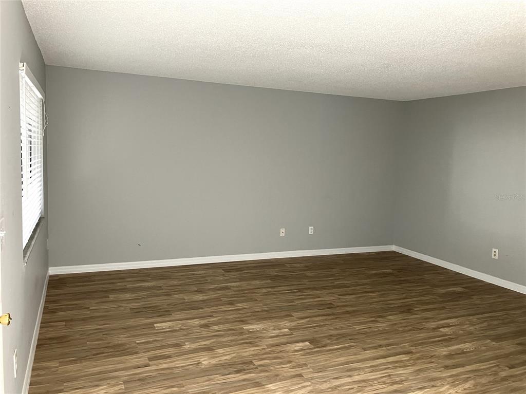 11703 Raintree Village Boulevard, Unit B Temple Terrace, FL 33617 - Photo 9 of 60 a view of an empty room with wooden floor and a window