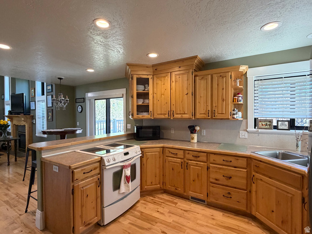 202 375 West Providence, UT 84332 - Photo 9 of 61 Kitchen placed in it's own corner yet close enough to be a part of everything, featuring a peninsula, light wood-style floors, and a chandelier