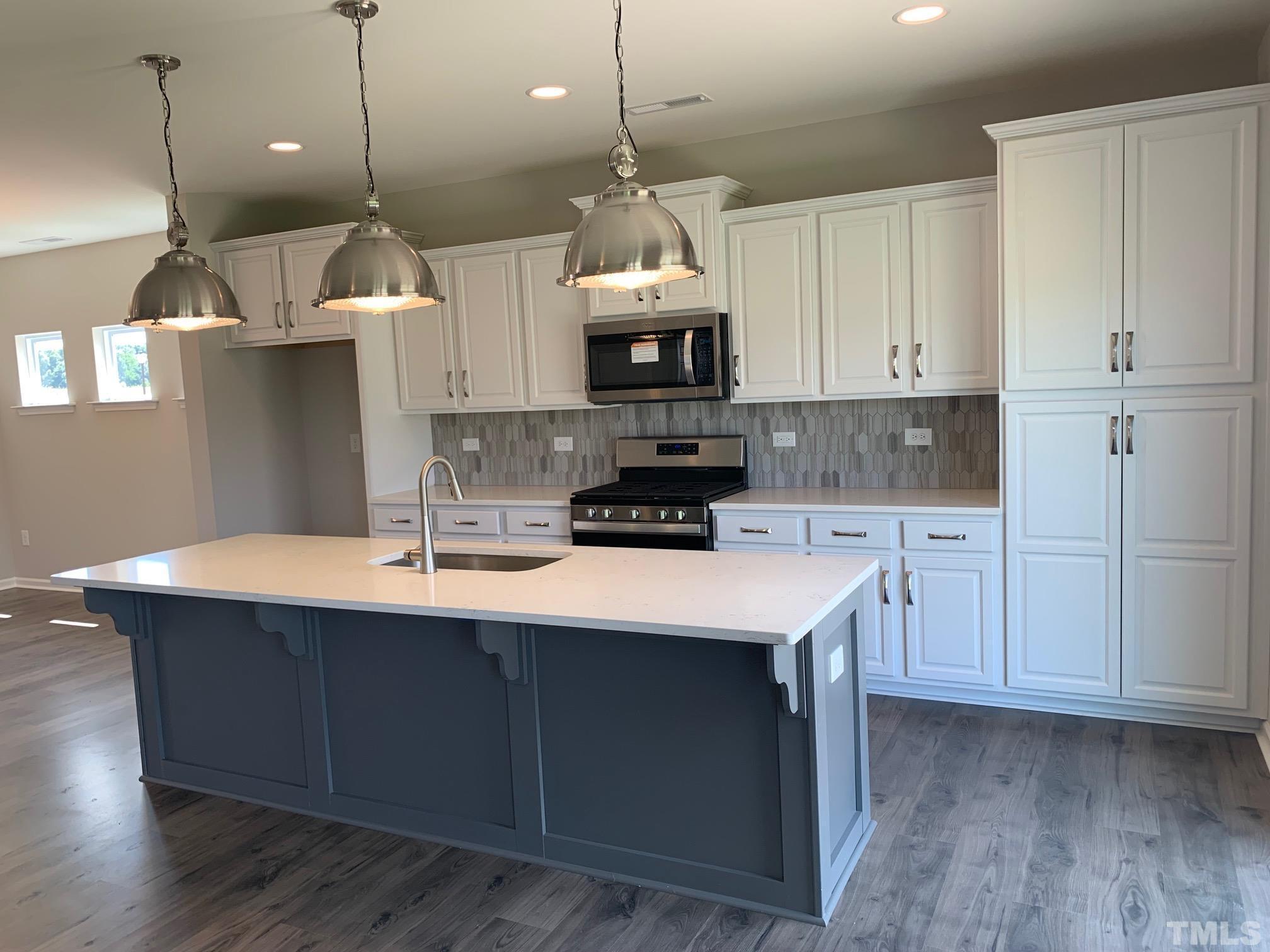 7104 Commodity Court Mebane, NC 27302 - Photo 12 of 32 a kitchen with stainless steel appliances granite countertop a sink a stove a refrigerator and white cabinets