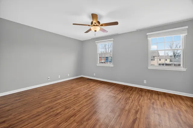 a view of empty room with wooden floor and fan