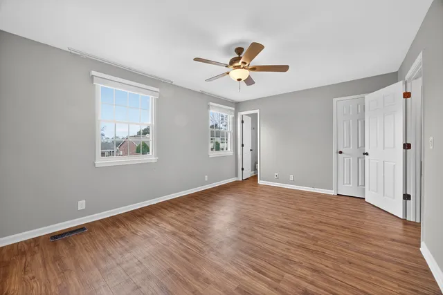 a view of empty room with wooden floor and fan