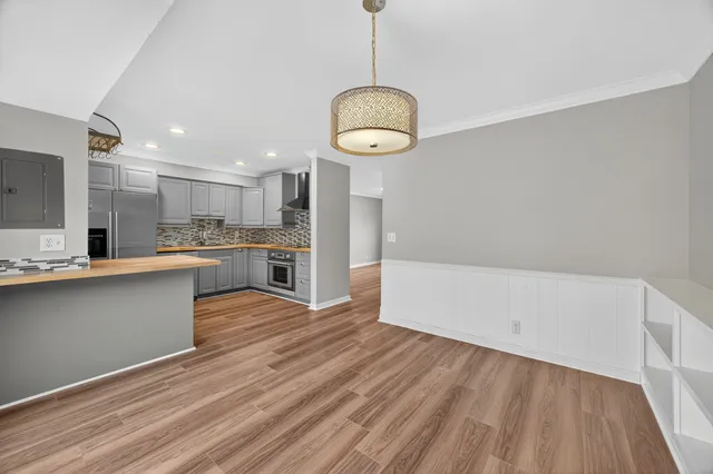 a kitchen with stainless steel appliances granite countertop a refrigerator a sink dishwasher a stove and white countertops with wooden floor