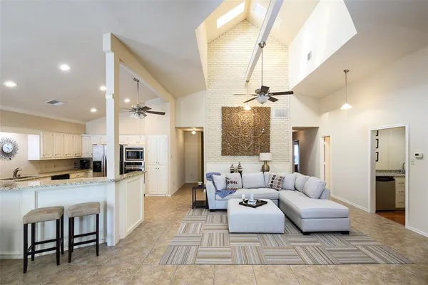 a living room with stainless steel appliances furniture and a kitchen view